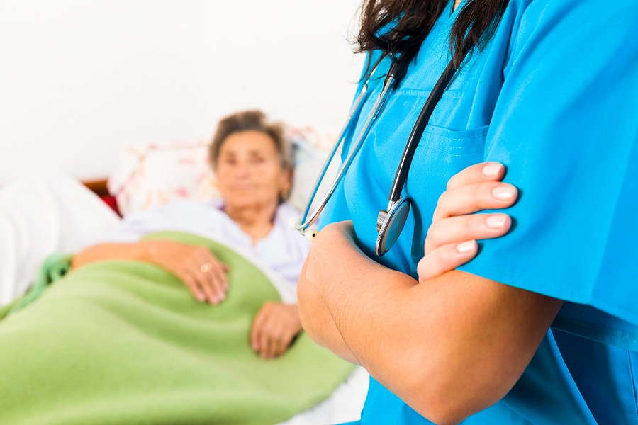 Nurse with folded arms looking over old person